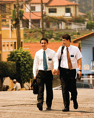 Two young men in white shirts and ties carrying literature